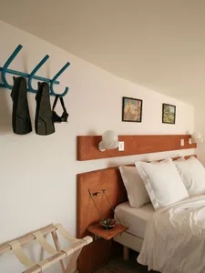 A modern bedroom with wooden paneling, white bedding, and framed pictures on the wall.