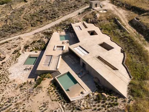 A modern house with a concrete exterior featuring pools and an exposed floor plan.