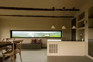 Spacious modern living room with a concrete floor, wooden furniture, and floor-to-ceiling windows overlooking scenic mountain