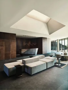 An expansive modern lobby featuring concrete furniture and a sleek, minimalist design.
