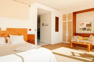 A modern minimalist bedroom featuring wooden furniture and woven fiber accents, with a bed, sofa, and coffee table.