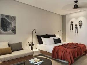 Minimalist bedroom with a wooden platform bed, white sheets, and a red throw blanket.