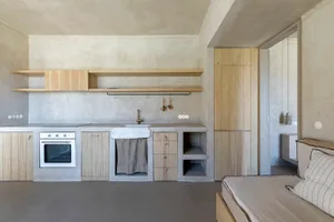 A minimalistic kitchen with concrete countertops and wooden shelves.