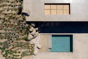 An aerial view of a modern residential space featuring a concrete and glass pool design.
