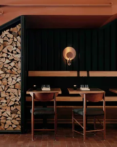 Modern restaurant booth made of wood with black walls and seating.