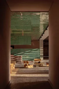 Modern interior of a restaurant with green tile walls and wooden furniture.