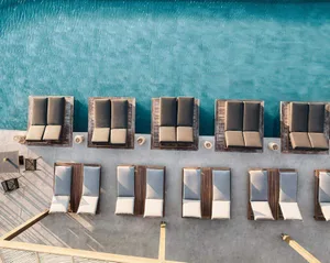 Aerial view of a poolside seating area with wooden loungers and cushions.