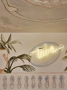 A photograph of a retail interior with painted walls and a neon sign that reads 'tuba'.
