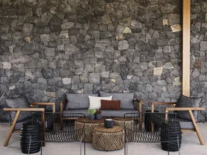 A living room with a natural stone wall and upholstered furniture.