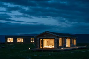 A rustic home with wooden exterior and illuminated windows at night.
