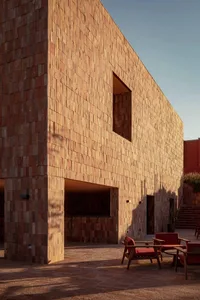 A modern building made of red bricks with a paved courtyard.