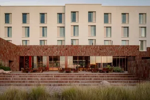 Modern hotel lobby featuring sandstone and wood materials, with a minimalist design approach.