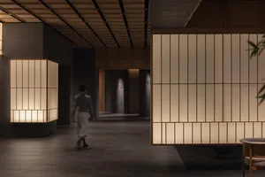 A modern lobby with concrete and wood paneling and a person walking through it.