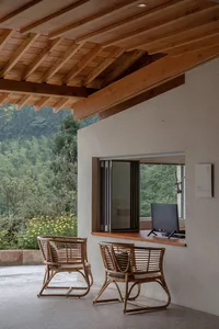 A contemporary reception desk made of wood with a computer and a window overlooking a scenic outdoor view.
