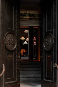A luxurious hotel lobby with black metal doors adorned with leather and marble