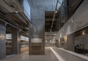 Industrial-style commercial kitchen with concrete pillars and exposed steel beams and pipes.