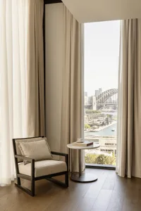 A minimalist living room with neutral-toned furnishings and large windows overlooking a cityscape.