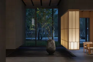 極簡風格的大廳，設有混凝土花盆與植栽、大型窗戶，以及溫暖燈光。