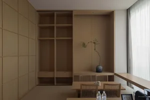 A minimalist wooden space with a dining area and built-in shelves.