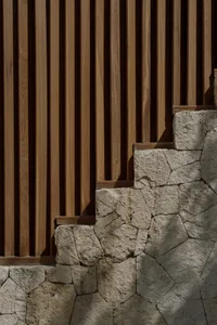 A modern architectural design featuring a wall made of wooden slats and stone blocks.