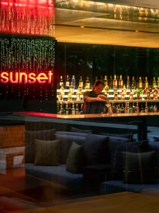 A modern bar area with glass shelves, metal accents, and wooden seating.
