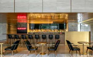 A sleek, modern bar area with metallic surfaces and a large assortment of liquor bottles.