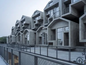 Modern concrete townhouses with exposed concrete walls and balconies.