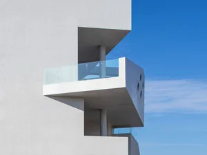 Modern concrete facade with glass balcony.