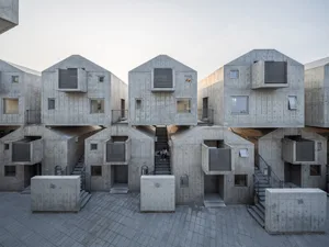 Modern residential buildings constructed with concrete units, featuring geometric shapes and uniform design.