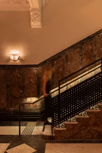 A woman walking down a modern staircase made of marble.