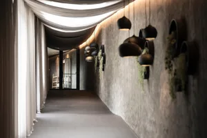Modern minimalist corridor with concrete walls, black pendant lights, and hanging greenery.