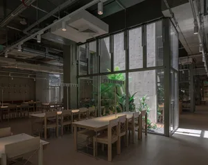 A modern office cafeteria with concrete, glass, and wooden elements.