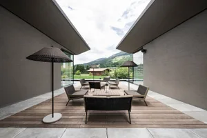 Modern patio area featuring outdoor furniture with woven seats and umbrellas under a ceiling.