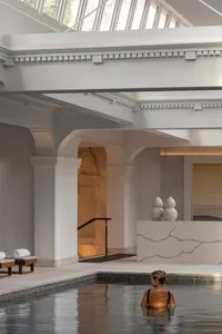 A woman relaxing in a modern indoor relaxation pool made of concrete.