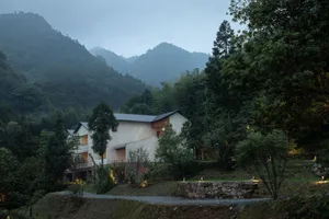 A modern residential exterior with concrete walls and a sloped roof in a forested area.