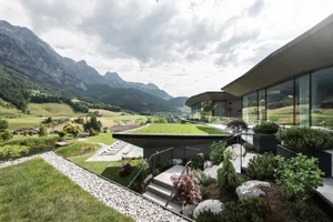 Modern residential home with glass roof and rooftop garden overlooking a scenic mountain landscape.