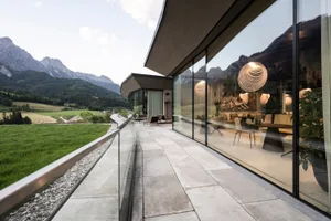 A modern residential interior featuring glass walls and concrete flooring.