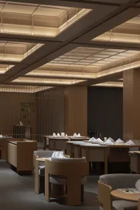 Modern restaurant interior with wooden tables and chairs, elegant lighting, and minimalist design