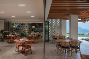 Modern restaurant interior with wood tables, stone walls, and glass accents.