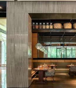 Modern restaurant interior with wooden tables, chairs, and shelves displaying jars and baskets.
