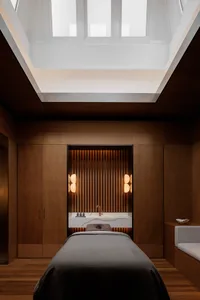 Modern spa room featuring a wooden wall and skylight with a massage table in the foreground.