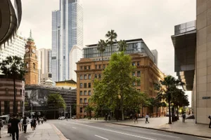 充滿活力的城市街景，展現混凝土、玻璃與磚牆的現代建築，外圍環繞棕櫚樹