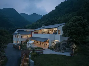 A modern mountain residence featuring concrete and glass materials in a serene outdoor setting.