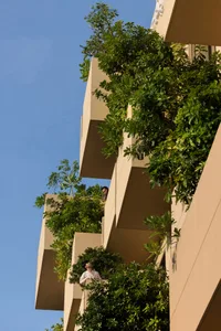 Apartment building with green balconies covered in lush vegetation, featuring concrete exterior.
