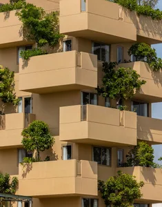 A modern, multi-story residential building featuring concrete discs with plants growing on them.