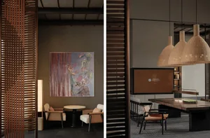 A minimalist hotel lobby features a wooden table, chairs, and a hanging rattan light fixture.