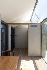 A minimalistic interior space featuring a wooden floor and a window with sunlight streaming in.