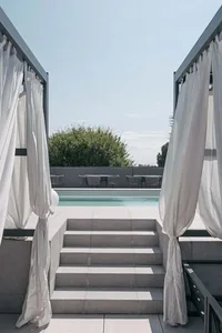 Concrete steps leading to a minimalist residential landscape with seating area and pool.