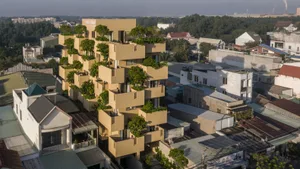 An aerial view of a modern apartment building with concrete balconies featuring green vegetation.