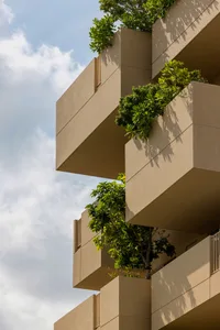 A modern architectural building with concrete balconies and greenery.